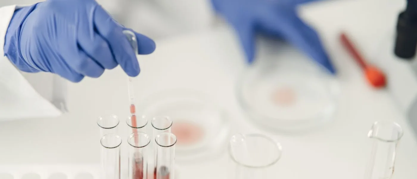 Main gantée de laboratoire au-dessus d'éprouvettes pendant une analyse d'échantillon